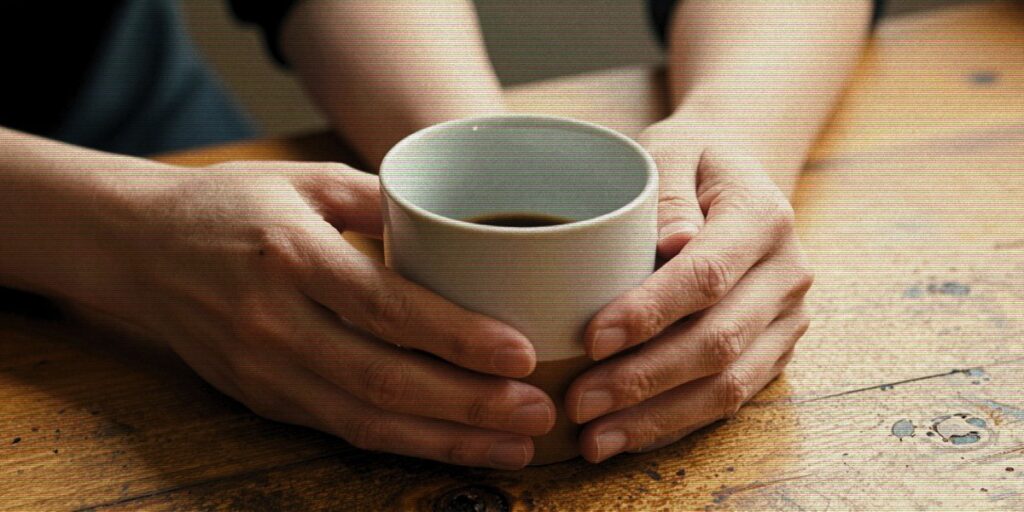 Mãos segurando xícara de café em pausa — procrastinação como sinal emocional
